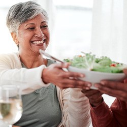 Smiling woman grabbing bowl of salad