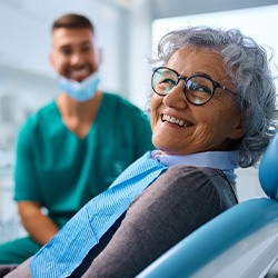 Woman with black glasses smiling in treatment chair