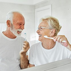 Senior couple smiling while brushing their teeth