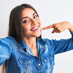 Smiling woman pointing to her white teeth