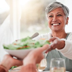 Woman smiling while grabbing bowl of salad