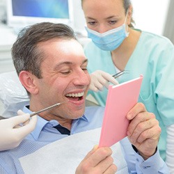 A man looking in the mirror at his dental implants