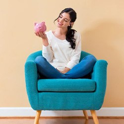 Woman sitting a chair and holding a piggy bank
