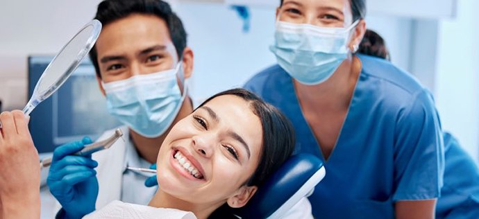 Happy patient posing with her dental team