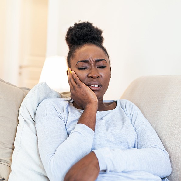 Woman on couch experiencing toothache