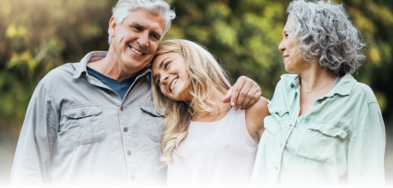 Woman hugging and laughing with her parents outdoors