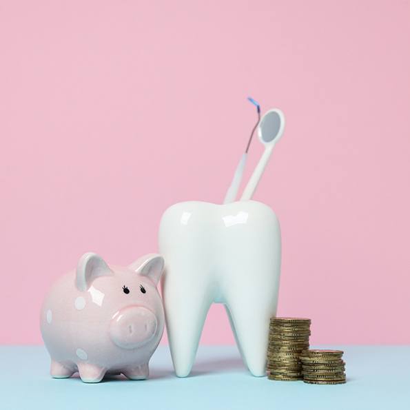 Pink piggy bank next to model tooth and pile of coins with pink background