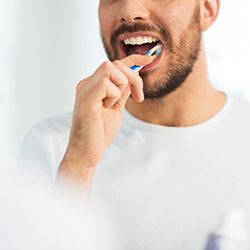 Man in white shirt brushing teeth
