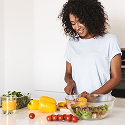 Woman smiling while cutting vegetables in kitchen