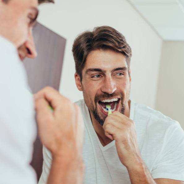 a man with a bright smile brushing his teeth