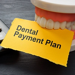 Artificial teeth biting paper that reads “Dental Payment Plan”