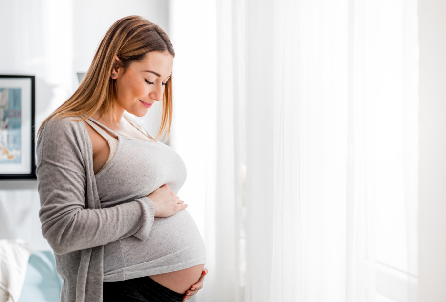Pregnant woman smiling at stomach